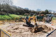 boy pictured on a toy digger digging sand
