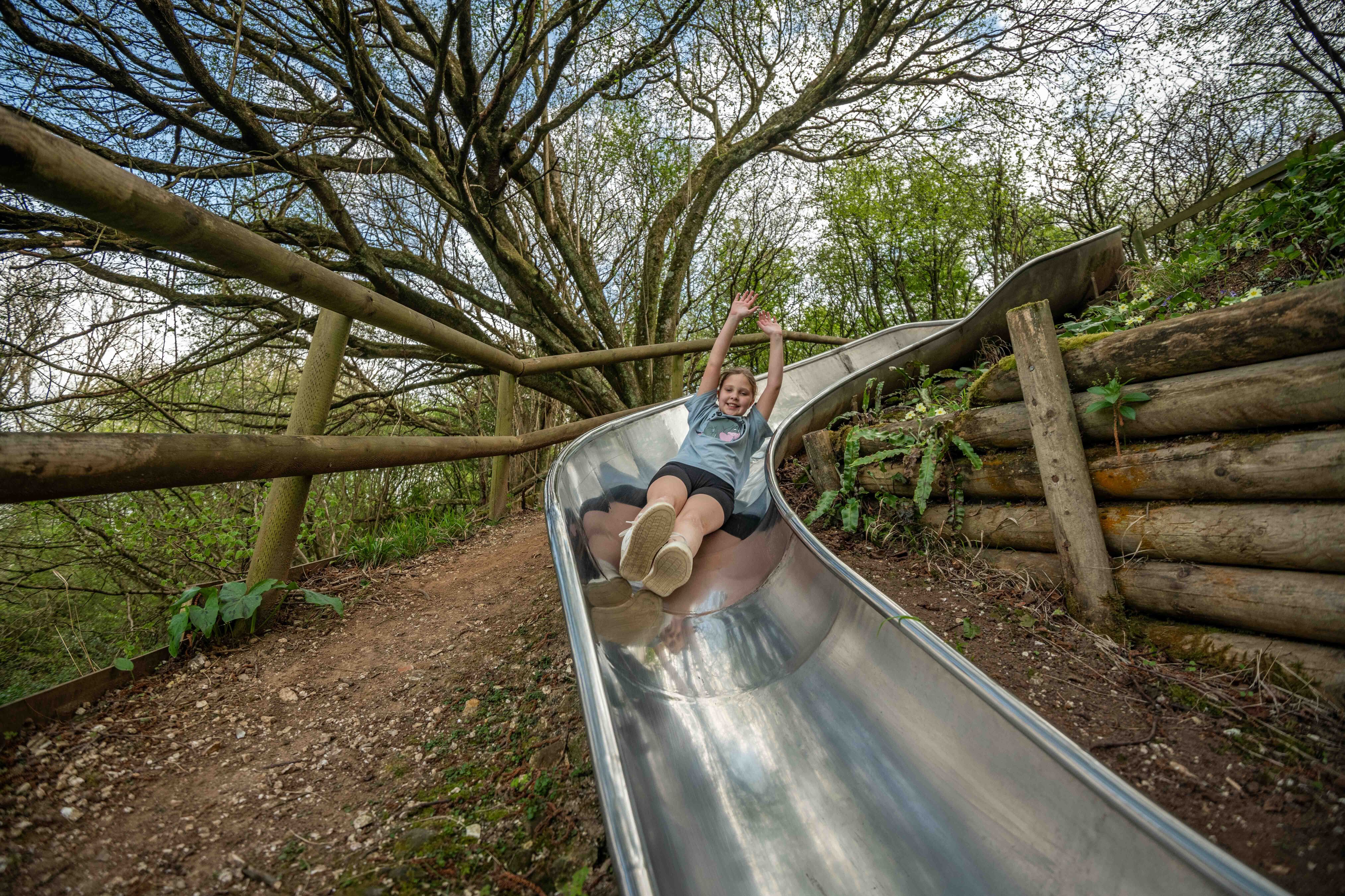 Girl smiling whilst on slide, with her hands in the air with joy