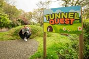 Young girl playing in tunnels with sign saying 'Tunnel Quest'