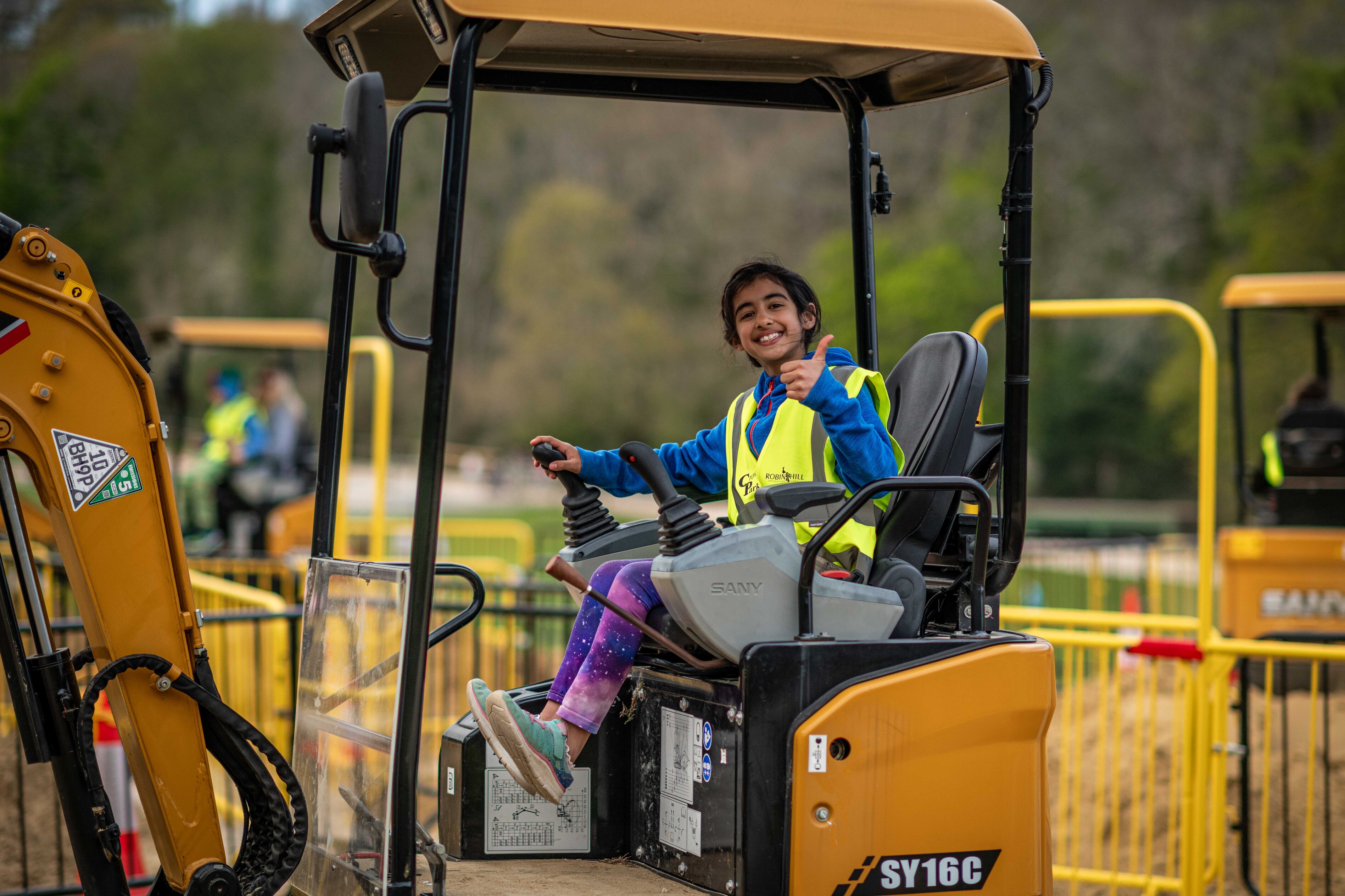 young girl smiling whilst on a toy digger