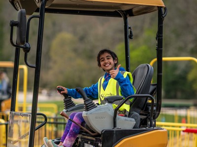 young girl smiling whilst on a toy digger