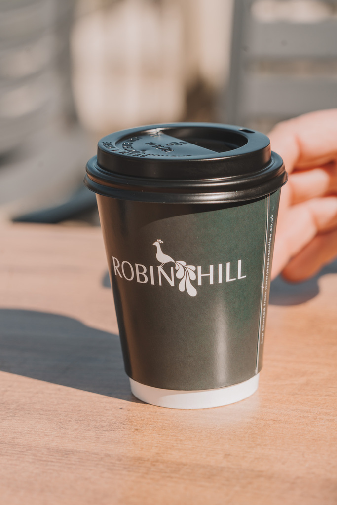 Green disposable coffee cup with Robin Hill Adventure park logo