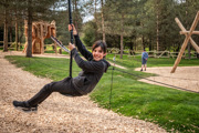 teen boy smiling whilst on zipline in forrest play ground