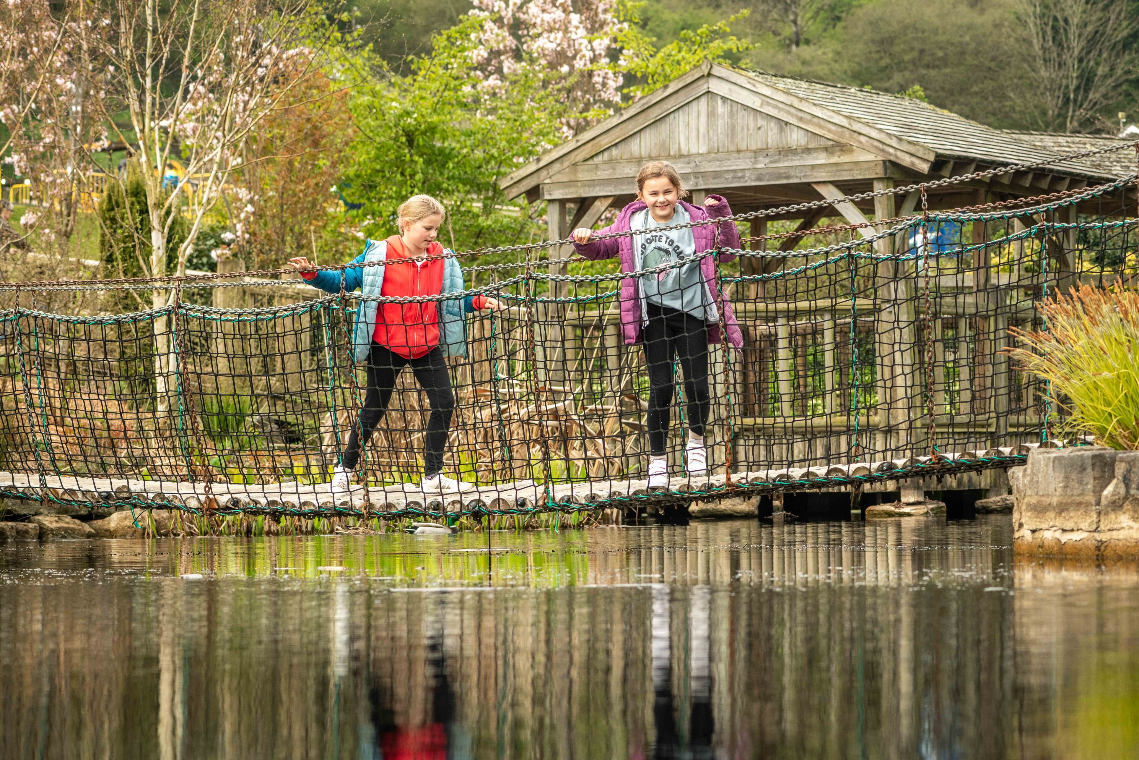 Two young girls on bridge over pond