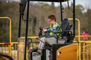 young boy with ginger hair and glasses playing on toy digger