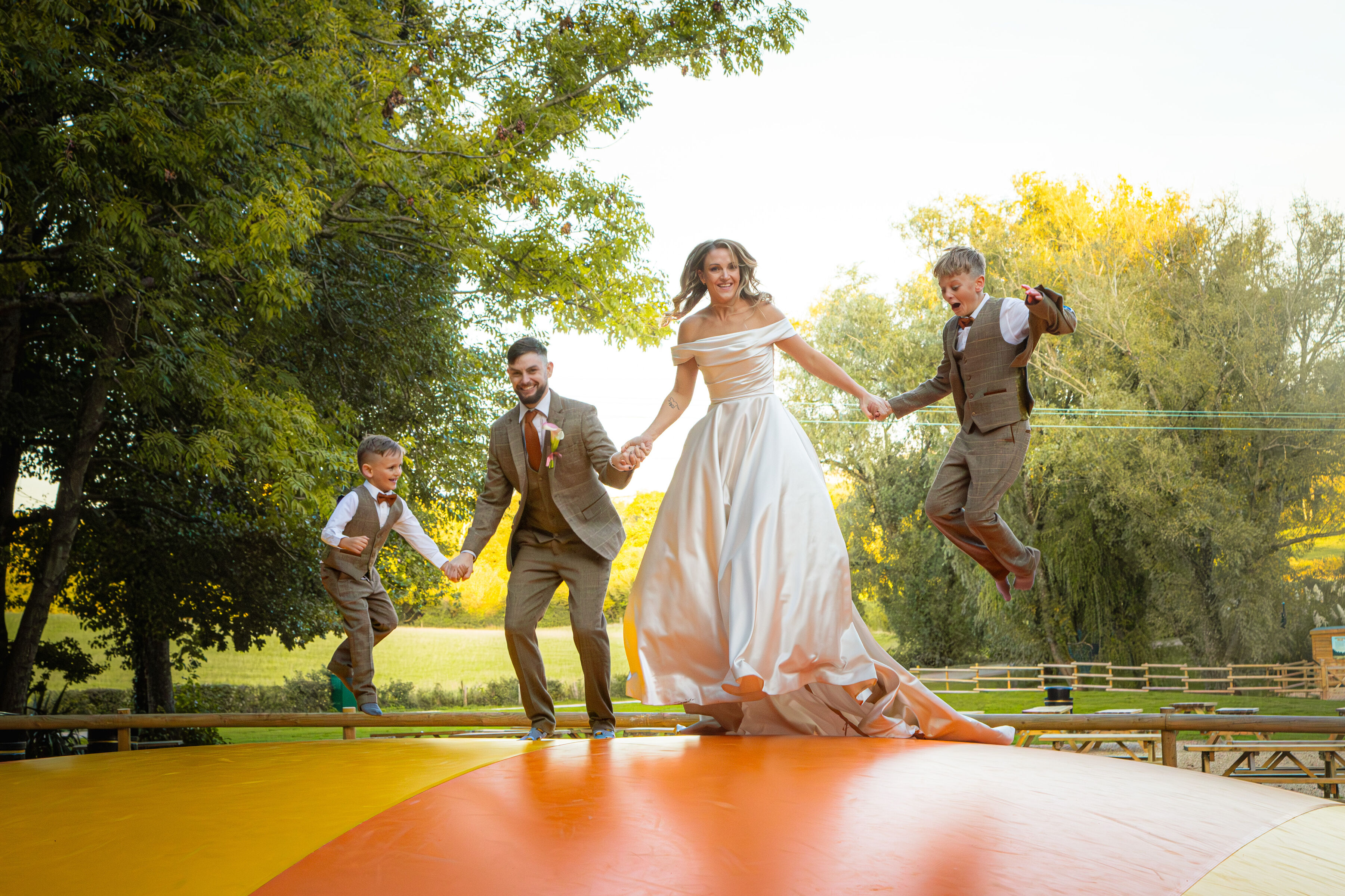Family on their wedding day jumping on large inflatable pillow