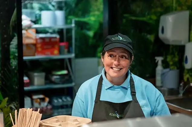 Lady smiling whilst serving customer at a cafe