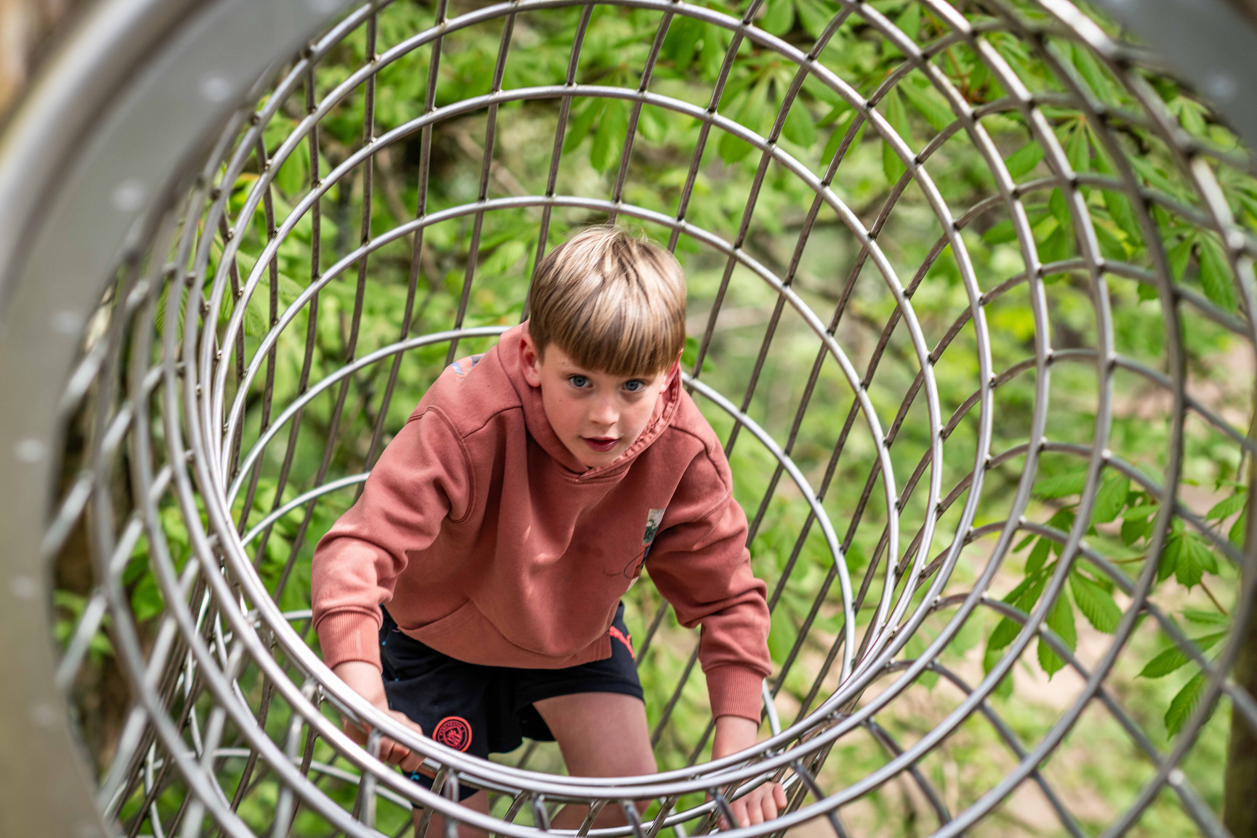 Young boy playing on metal tunnel