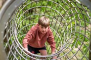 Young boy playing on metal tunnel