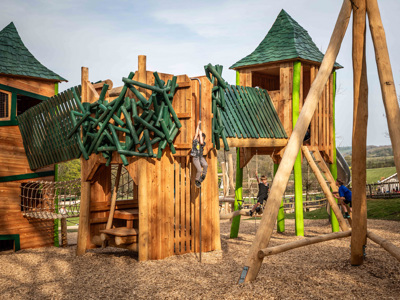 Large wooden play area with child playing on it 