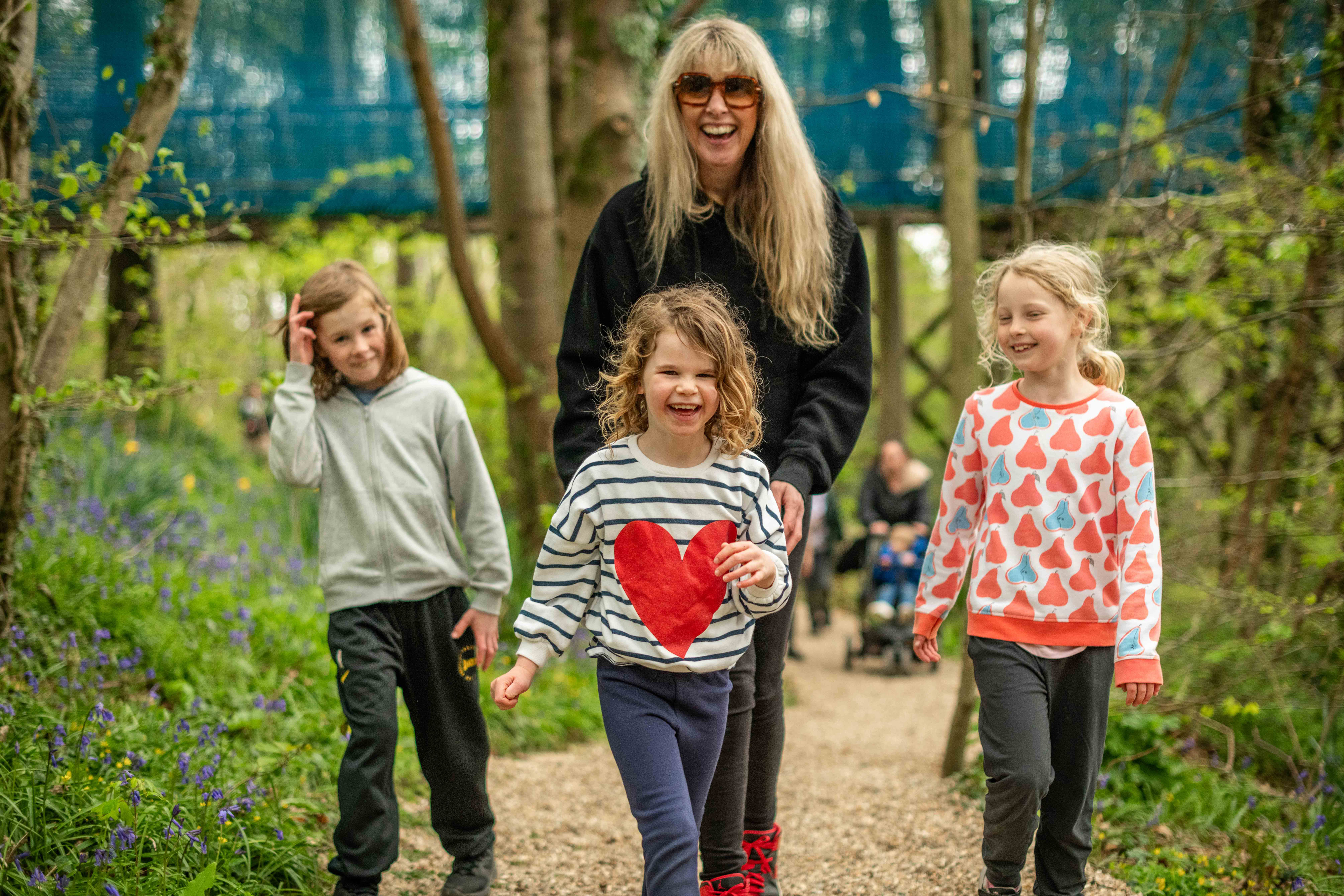 Family (mother, son and two daughters) smiling and laughing whilst walking through forest
