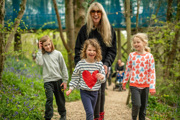 Family (mother, son and two daughters) smiling and laughing whilst walking through forest